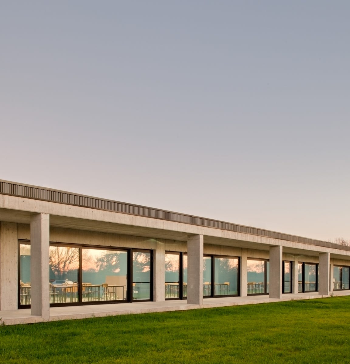 Foto esterni dell’ampliamento dell’Istituto Agrario Domenico Sartor a Castelfranco Veneto (TV), progettato da MD41, edificio su un piano con ampie vetrate e portico perimetrale.