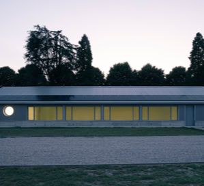 Vista esterna della mensa scolastica di Villa del Conte con facciata vetrata, copertura a falde e pannelli fotovoltaici