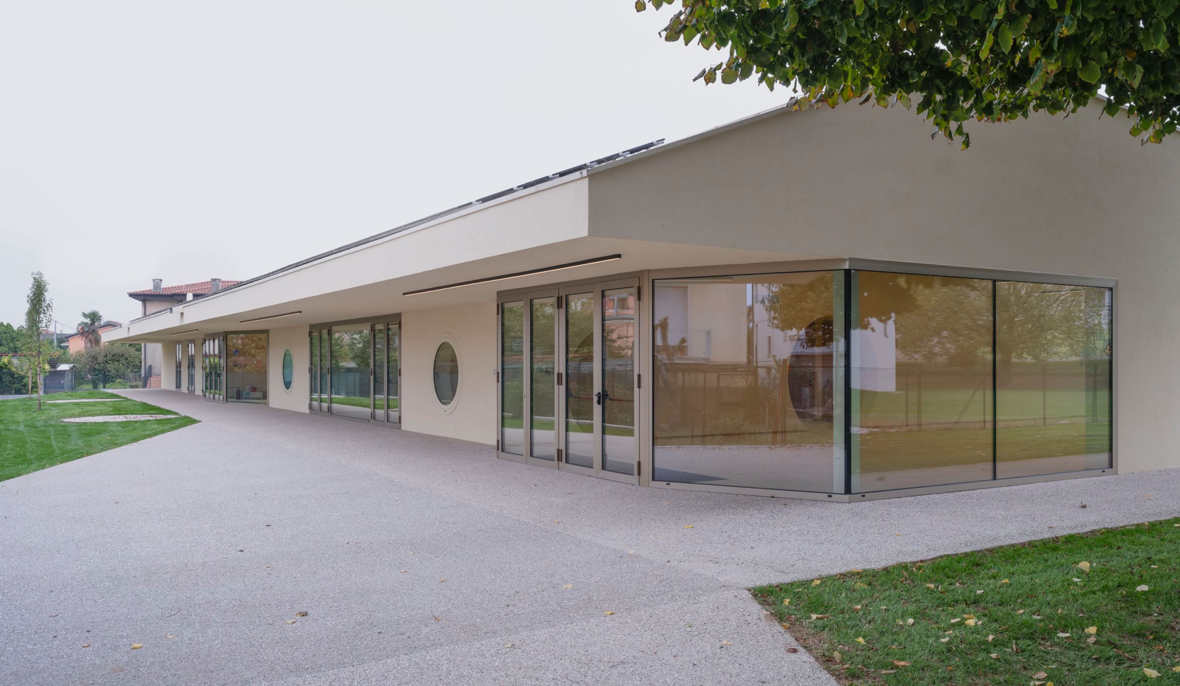 Foto esterni del nuovo polo dell’infanzia a Longare (VI), progettato da MD41, edificio con tetto a falde scultoreo, accessi distinti e ampi spazi esterni.
