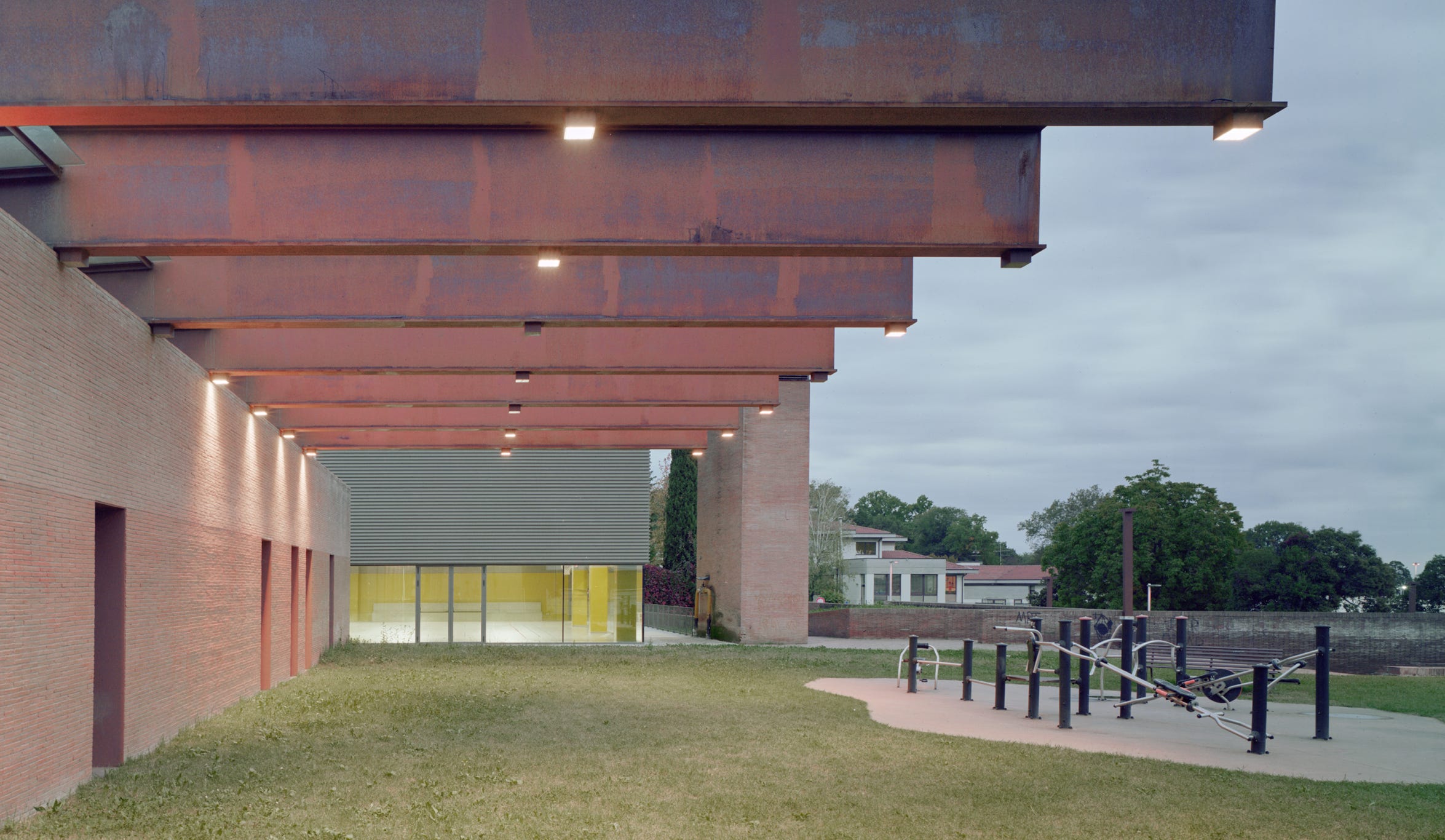 Foto esterni della nuova palestra scolastica a Merate (LC), progettata da MD41, edificio su un piano con grande vetrata e design contemporaneo.