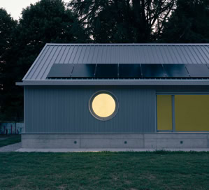 Vista esterna della mensa scolastica di Villa del Conte con facciata vetrata, copertura a falde e pannelli fotovoltaici