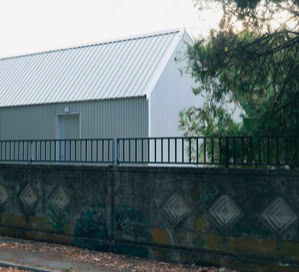 Vista esterna della mensa scolastica di Villa del Conte con facciata vetrata, copertura a falde e pannelli fotovoltaici